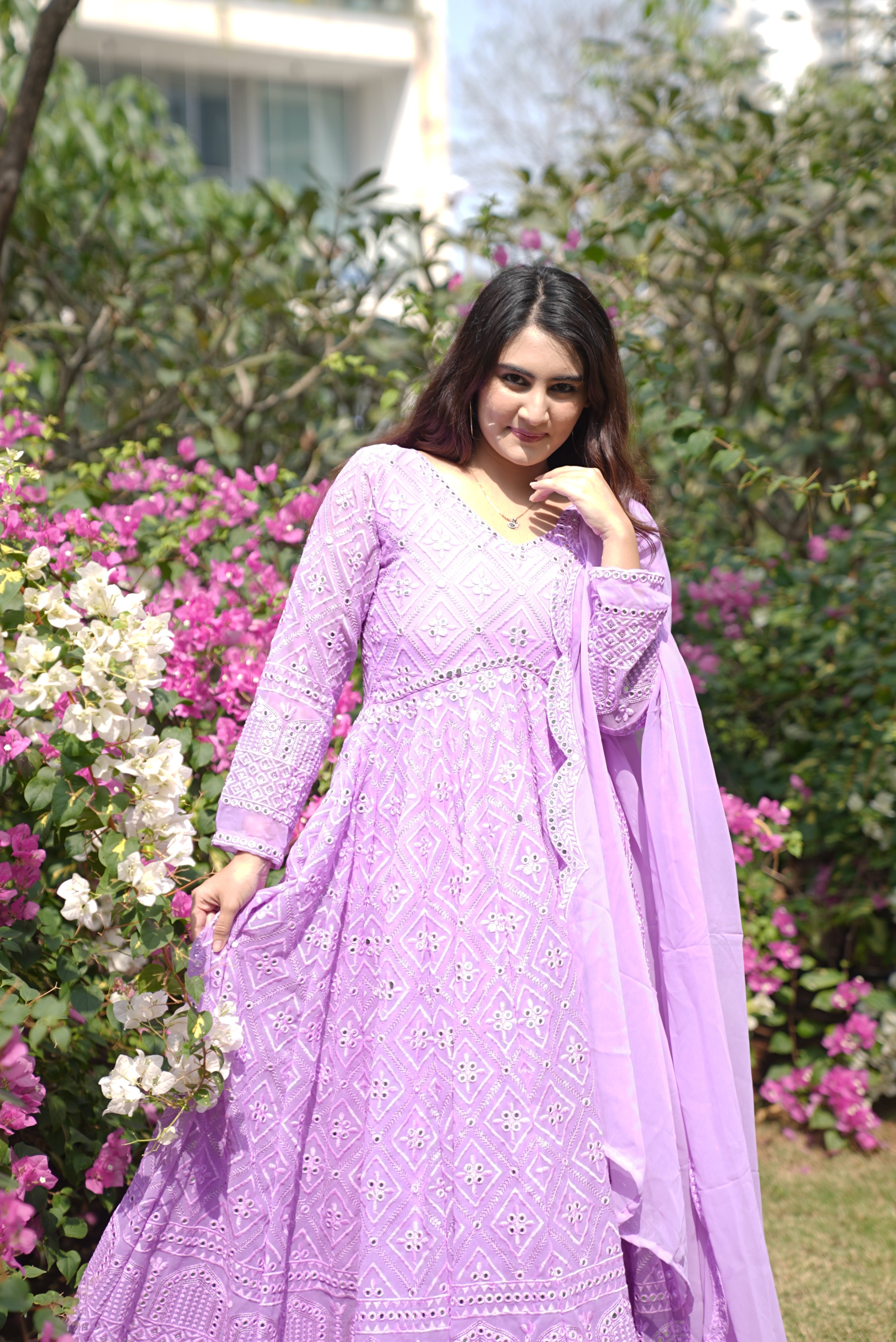 Woman in a purple traditional outfit standing among flowers